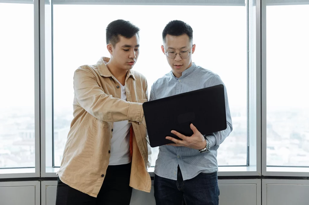 photographie de deux hommes dans un bureau entrain de regarder un ordinateur
